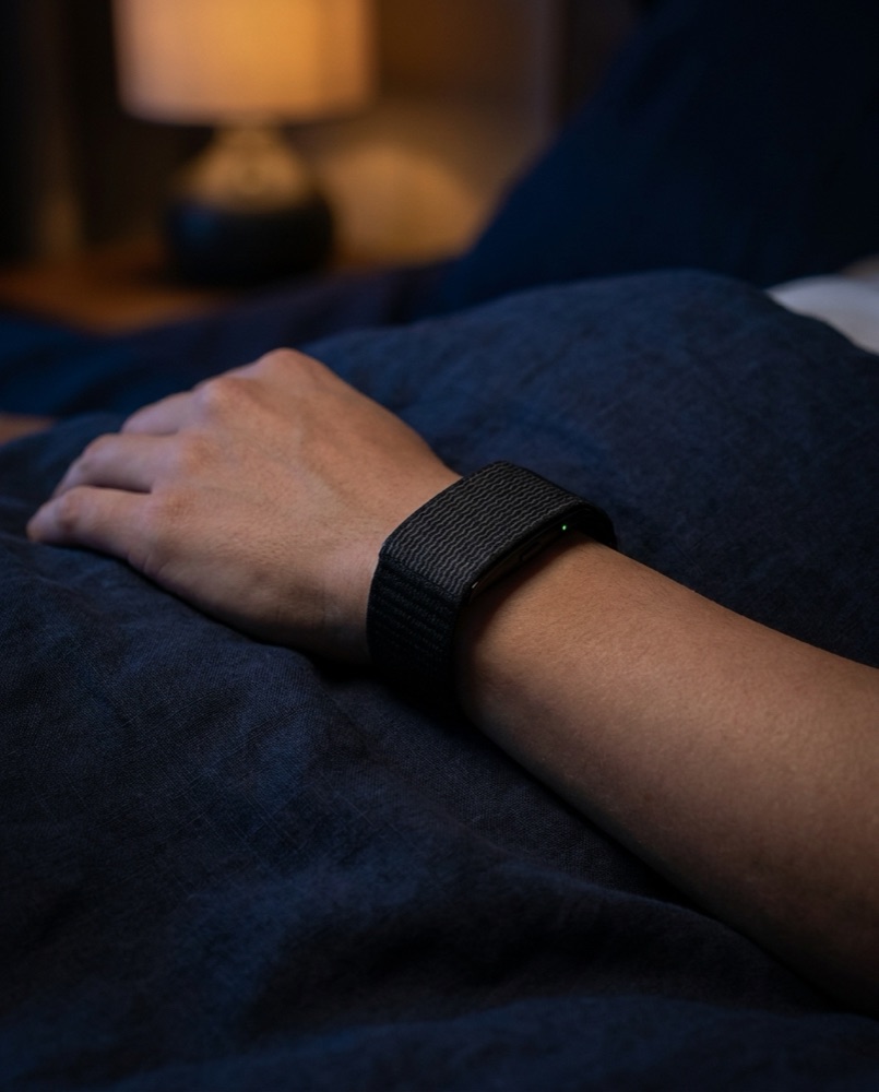 Primer plano de la pulsera Biometriv en la muñeca, de noche, sobre la cama